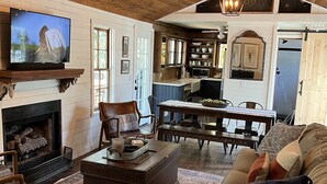 Een gezellige woonkamer met een open haard, een televisie en een eethoek met een tafel en stoelen.