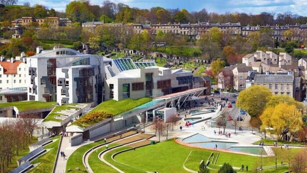 A modern building with a green roof, surrounded by a park with a central pond and walking paths. - Luxury Architect Designed Apt 13 Mins 2 Royalmile❤ (Edinburgh)