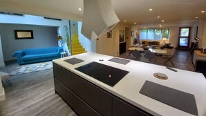 A modern kitchen with a central island, a dining area with chairs, a sofa, and a staircase leading to an upper level. - Luxury Architect Designed Apt 13 Mins 2 Royalmile❤ (Edinburgh)