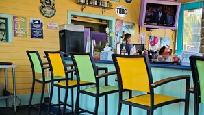 Un restaurante con sillas de colores, una zona de bar y varios letreros en las paredes.