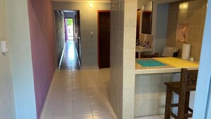 Een gang die leidt naar een badkamer met een spiegel, een wastafel en een stoel.