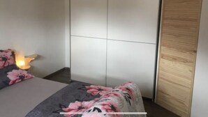 A bedroom with a bed, a nightstand, a wardrobe, and a wooden door.