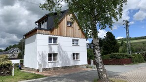 A two-story house with a white facade and a wooden upper section.