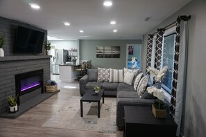 Ein modernes Wohnzimmer mit Kamin, einer Sofagarnitur, einem Couchtisch und einem an der Wand befestigten Fernseher.