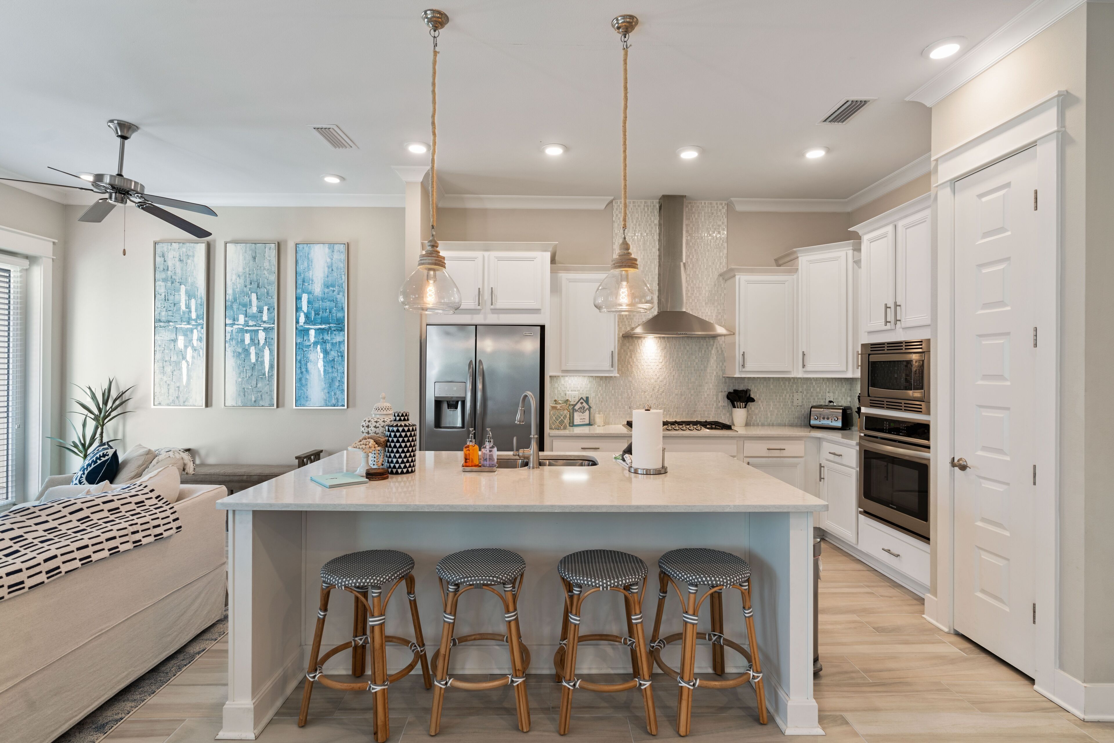 A modern kitchen with a central island, white cabinetry, and stainless steel appliances.