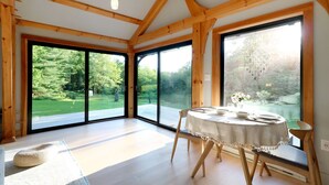 Un'ampia stanza con grandi finestre, un tavolo rotondo apparecchiato per la cena e travi in legno al soffitto.