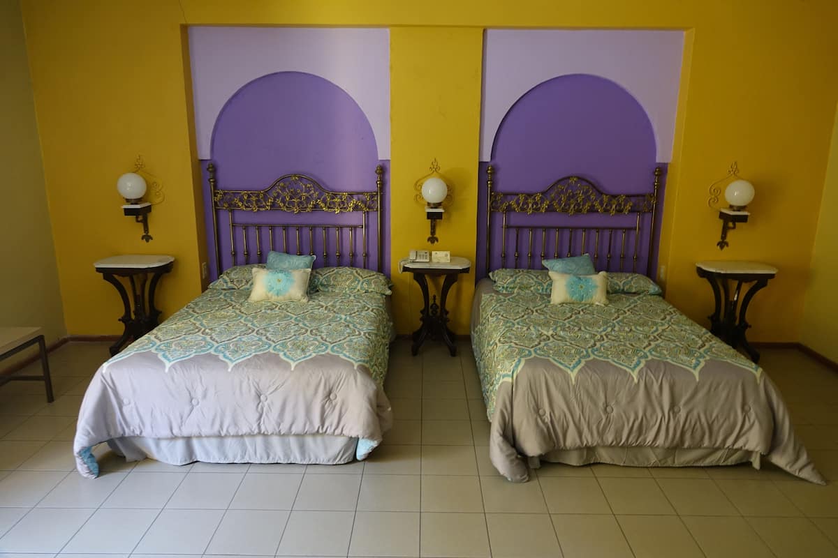 A room with two beds, each with a headboard and a nightstand.