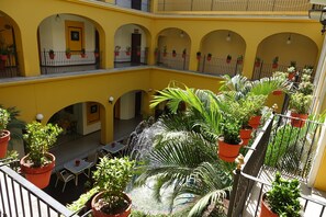 A multi-level courtyard with yellow walls, potted plants, and outdoor seating.