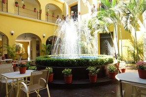 A courtyard with a central fountain, surrounded by potted plants and outdoor seating. - Hotel América Colima (Colima)