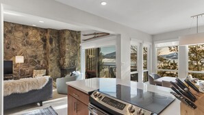A modern kitchen with a built-in stove, a dining area with a view, and a cozy seating area with a stone wall. - Summit Serenity: Luxury Alpine Ski Escape in Dillon, CO (Dillon)