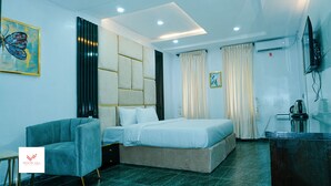 Quarto de hotel moderno com cama, sofá, escrivaninha e televisão.