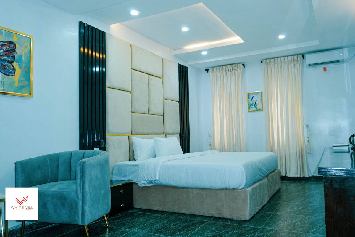 A modern hotel room with a bed, a sofa, a desk, and a television.