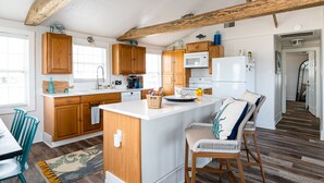 A modern kitchen with wooden cabinets, a white island, and a dining area with a table and chairs.