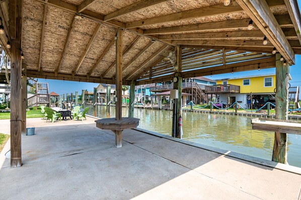 Un espace extérieur abrité, doté d’une structure en bois, d’une table centrale et de chaises.