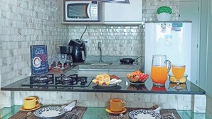 A modern kitchen with a microwave, kettle, and coffee machine. There are two glass tables with breakfast items. - Laguna Beach - Charming, furnished, and cozy loft-style apartment - 402 (Ipojuca)
