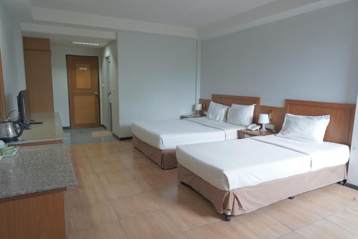 A hotel room with two beds, a desk, a mirror, and a door leading to another room.