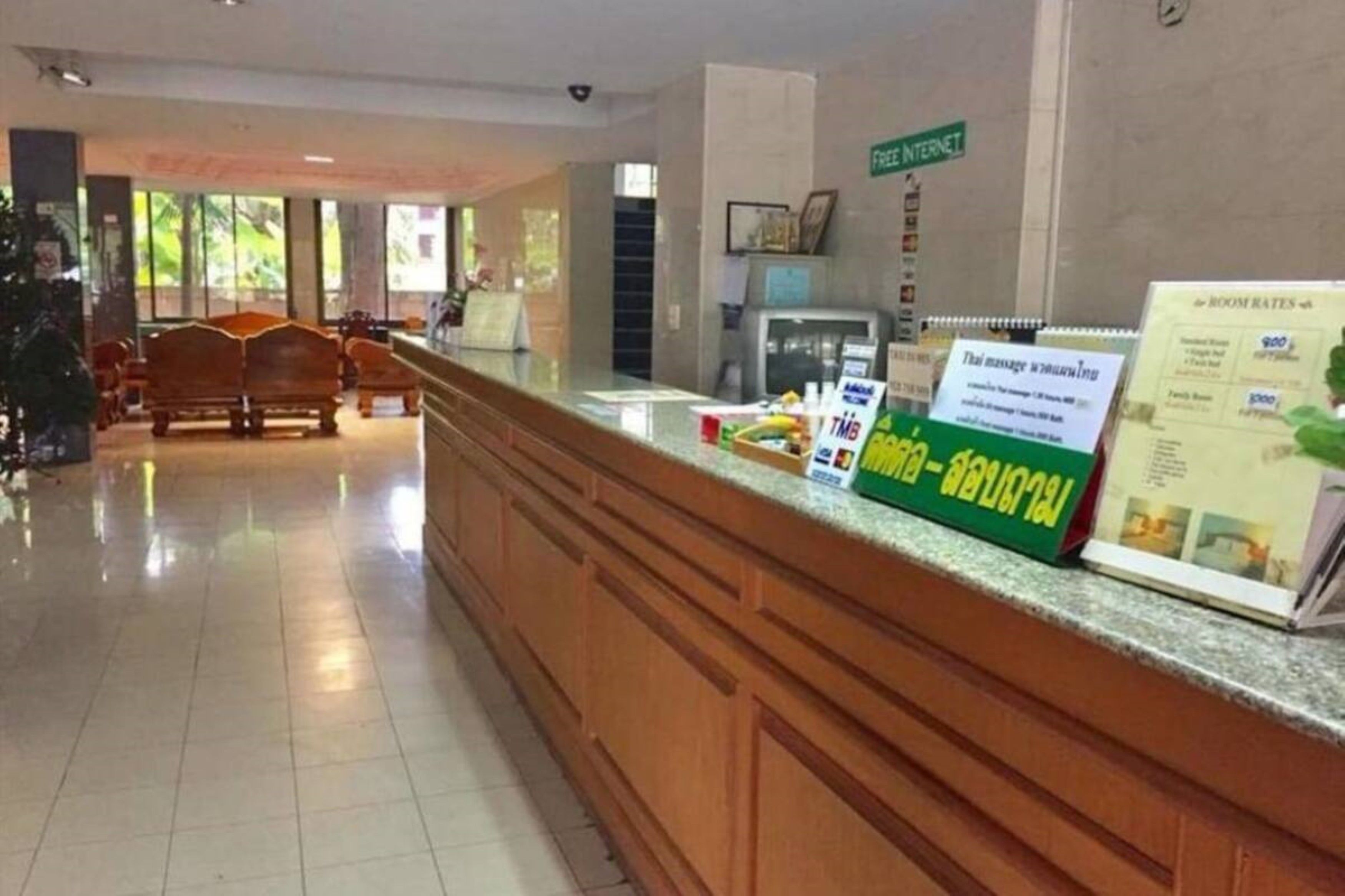 Zona de recepción de hotel con un mostrador de madera, un cartel que anuncia internet gratuito y folletos con tarifas de habitaciones.