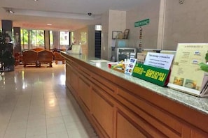 A hotel reception area with a wooden reception desk, a sign for free internet, and a brochure for room rates. - Sport Inn Chiang Rai by Zuzu (Chiang Rai)