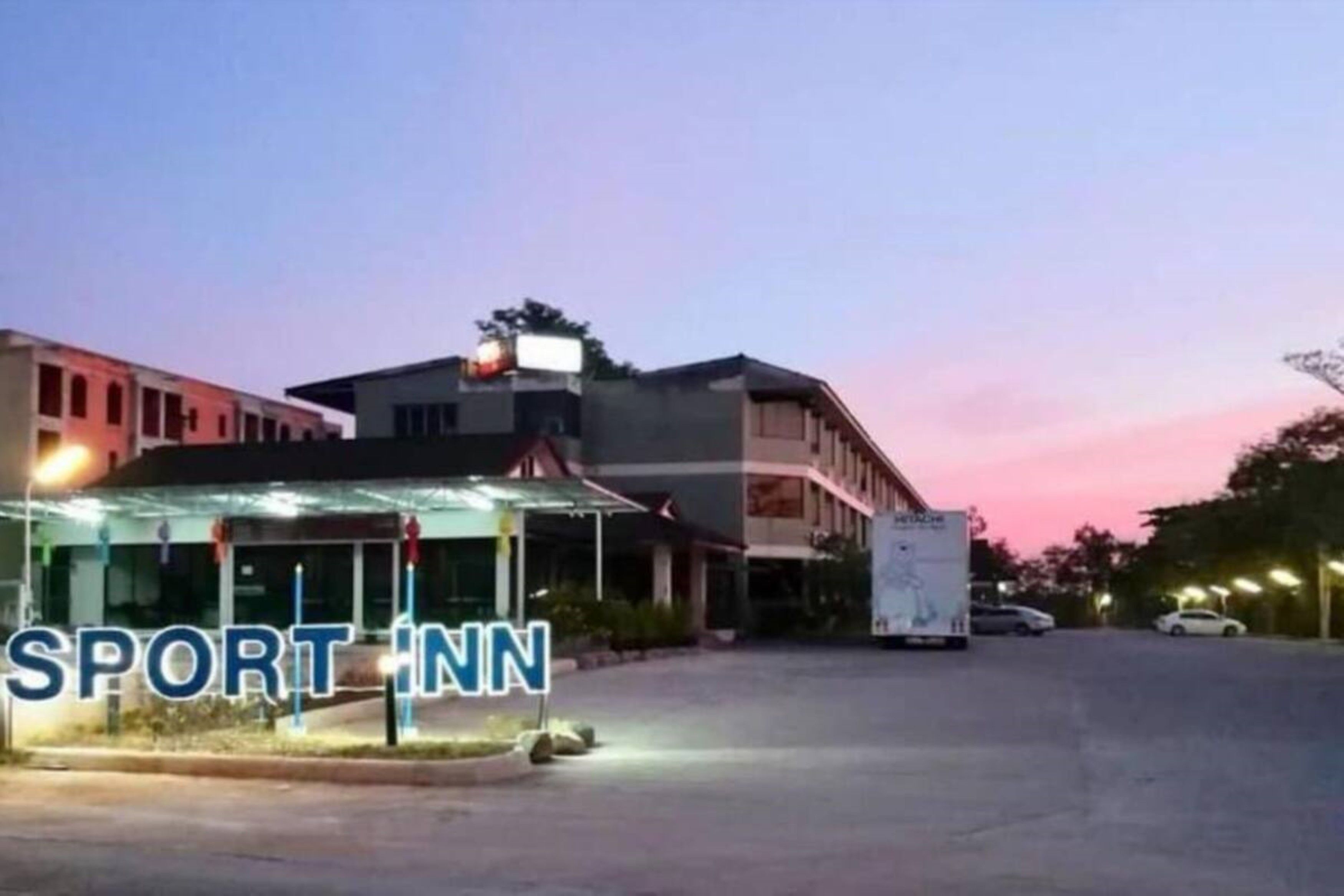 Un hôtel appelé SPORT INN, doté d’un design moderne, comprenant une entrée couverte et un espace de stationnement.