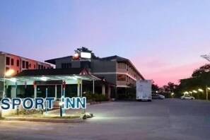 A hotel named SPORT INN with a modern design, featuring a covered entrance and a parking area.