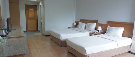 A hotel room with two beds, a desk, and a kitchenette.