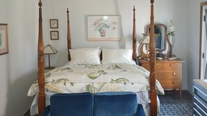 Un dormitorio con cama con dosel, candelabro, cómoda y espejo.