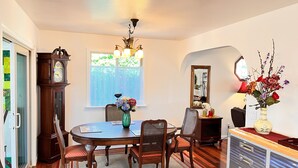 A dining room with a round table, chairs, a clock, a vase with flowers, and a mirror on the wall. - Serene Sonoma Home, Walk/bike downtown in minutes (Sonoma)