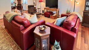 A living room with a red leather sofa, a wooden coffee table, a floor lamp, and a TV stand. - Serene Sonoma Home, Walk/bike downtown in minutes (Sonoma)