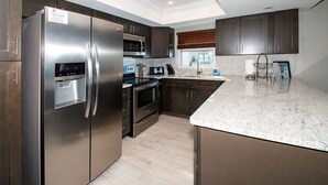 Una cocina moderna con electrodomésticos de acero inoxidable, armarios oscuros y una encimera de granito.