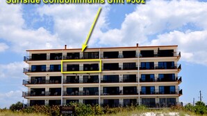 Edificio de apartamentos frente a la playa con varios balcones y un cartel que indica que es la Unidad #502.
