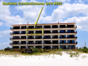 Un immeuble d’appartements de luxe situé en bord de mer, doté de nombreux balcons et d’une plaque indiquant qu’il s’agit de l’unité n° 502.