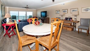 A dining area with a round table, wooden chairs, and a ceiling fan.