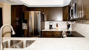 Una cocina moderna con electrodomésticos de acero inoxidable, armarios de madera oscura y encimera de granito.