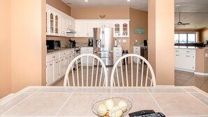 A modern kitchen with white cabinets, stainless steel appliances, and a dining area with a table and chairs.