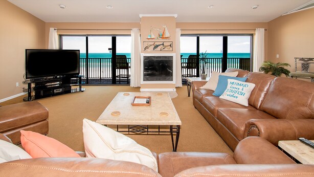 A living room with a TV, leather sofas, a coffee table, and a fireplace.