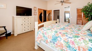 Une chambre à coucher comprenant un lit, une commode, un téléviseur et un ventilateur de plafond.