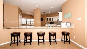 A kitchen with a large island, bar stools, and a view into the dining area.