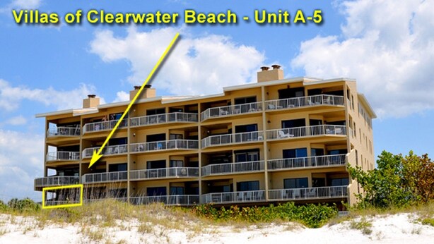 A multi-story hotel with balconies, located near a beach.