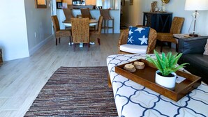 A living room with a sofa, a coffee table with a plant, and a patterned rug.