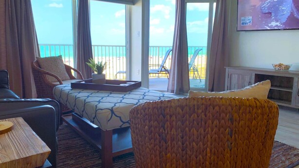 A hotel room with a bed, a wicker chair, a small table, and a TV on the wall.