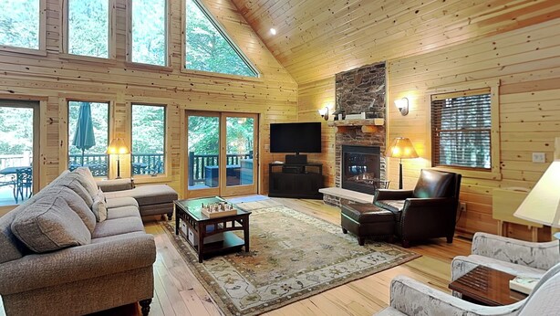 A spacious living room with a fireplace, large windows, and a cozy seating area. - Claralea Lodge by Taylor Made Deep Creek (Oakland)