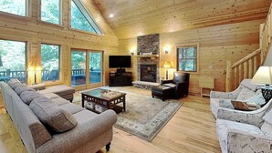 A spacious wooden interior with a large sofa, a fireplace, a television, and a pool view. - Claralea Lodge by Taylor Made Deep Creek (Oakland)