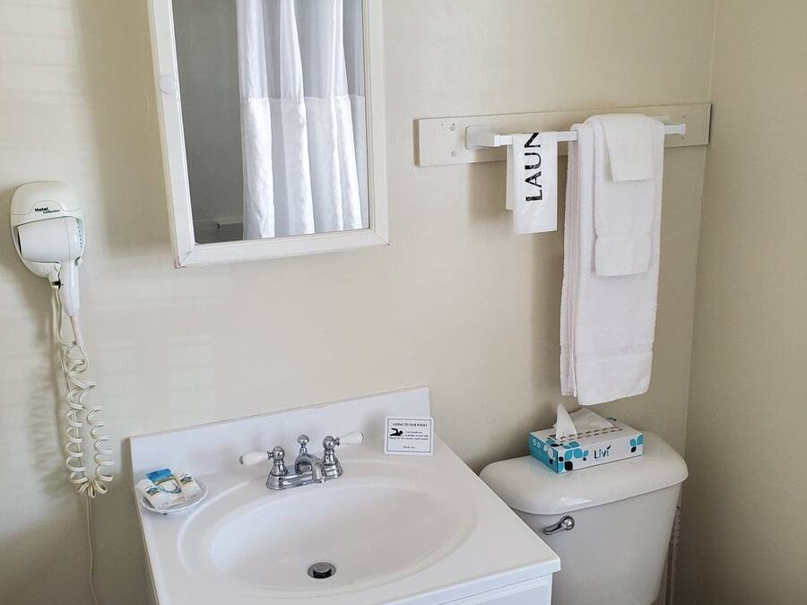 A bathroom with a white sink, a mirror, a toilet, and a towel rack.