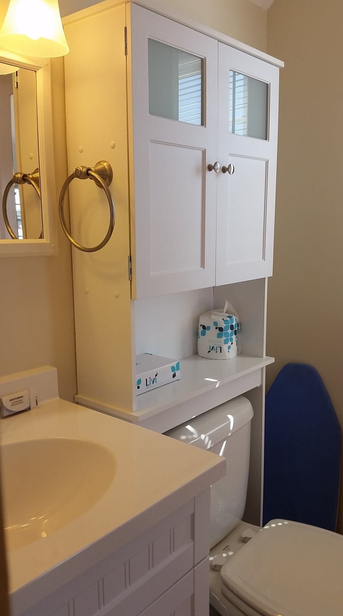 Un baño con lavamanos blanco, inodoro y un mueble con espejo.