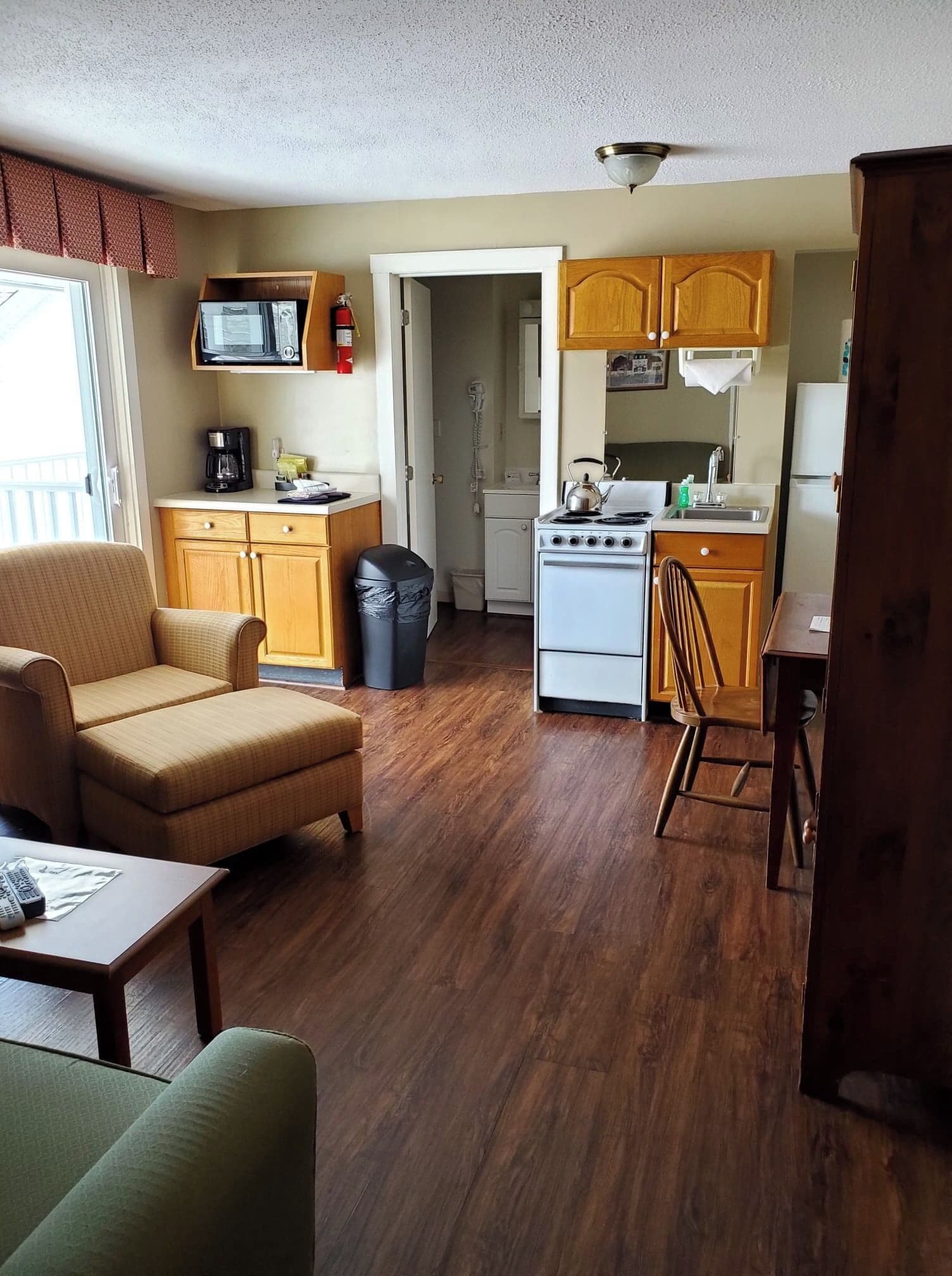 Un espacio habitable compacto con kitchenette, un sofá, una mesa de comedor y un cubo de basura.
