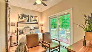 A bedroom with a bed, two chairs, a table, a ceiling fan, and a sliding glass door leading to a patio. - NEW! Modern Charlotte Hub in Lockwood Neighborhood (Charlotte)