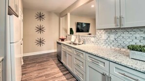 A modern kitchen with light grey cabinets, a granite countertop, and a backsplash with small tiles. - NEW! Modern Charlotte Hub in Lockwood Neighborhood (Charlotte)