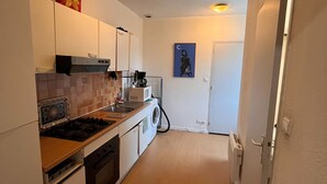Una cocina estrecha con gabinetes blancos, estufa, microondas y lavadora.