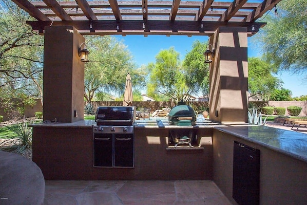 Um pátio externo com churrasqueira e pérgola.