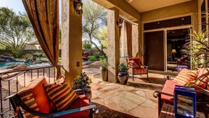 Un patio couvert avec une piscine, des sièges d’extérieur et un ventilateur de plafond.